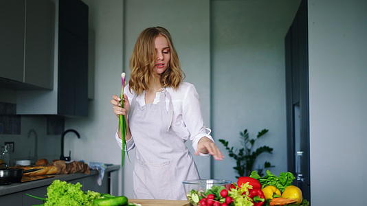 快乐女孩在厨房里用黄瓜当麦克风跳舞唱歌视频的预览图