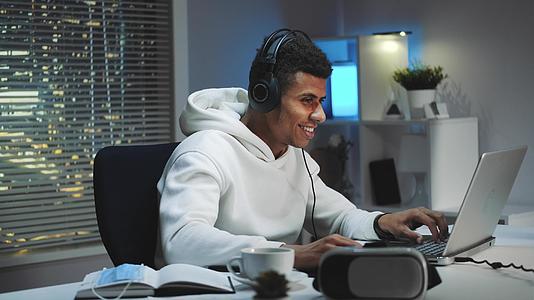 戴耳机的男人晚上在电脑上玩游戏视频的预览图