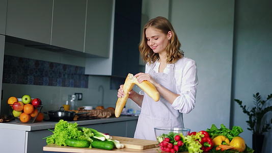 快乐的女孩在厨房里打破和吃法国面包视频的预览图