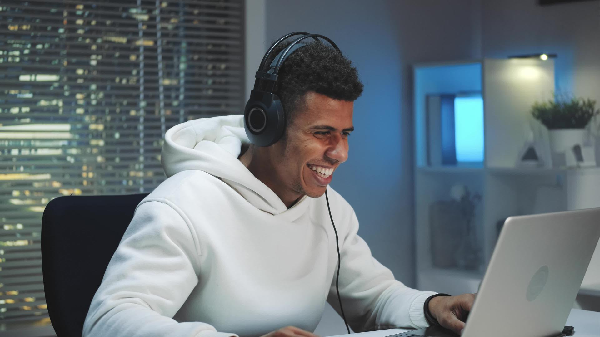 戴耳机的男人晚上在电脑上玩游戏很开心视频的预览图