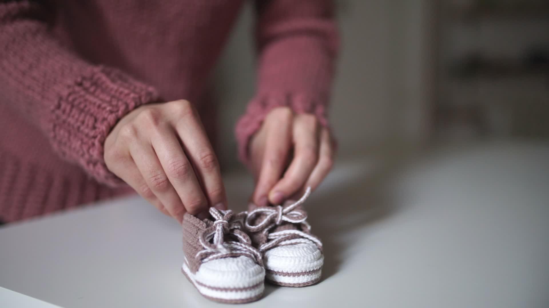 为了编织衣服妈妈玩粉色婴儿鞋视频的预览图
