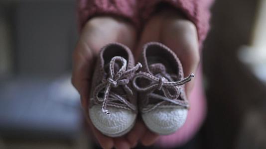 孕妈的手展示婴儿靴视频的预览图