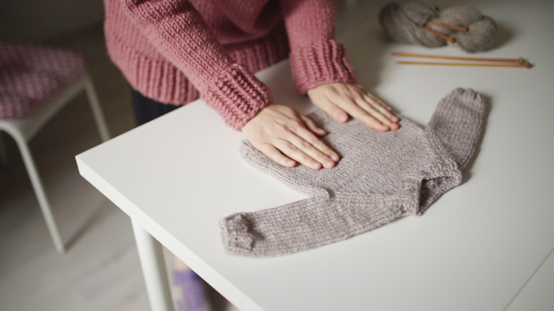妇女期望婴儿看着手织的毛衣躺在桌子上视频的预览图