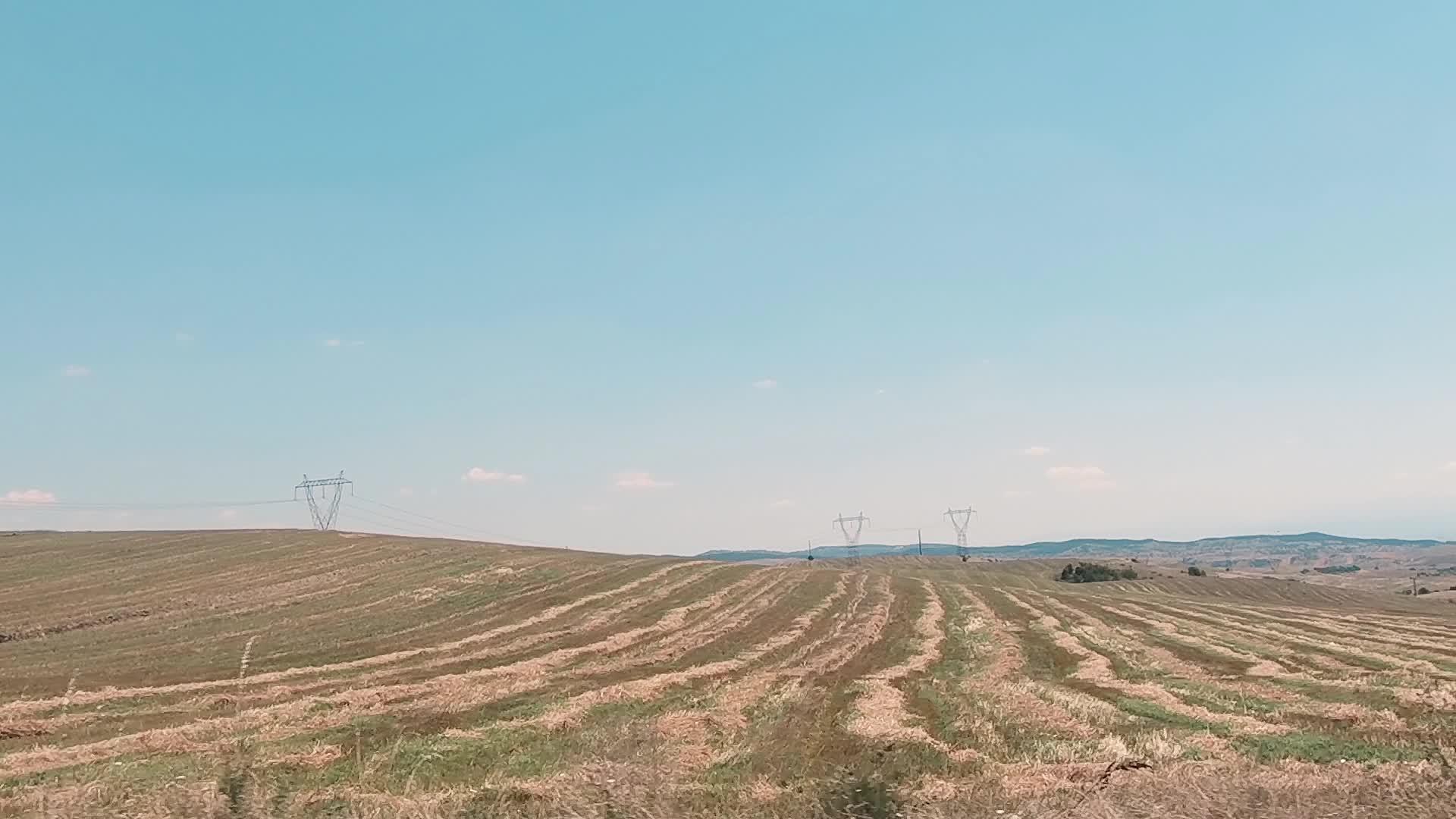沿着农村开车靠近电线塔和田地视频的预览图