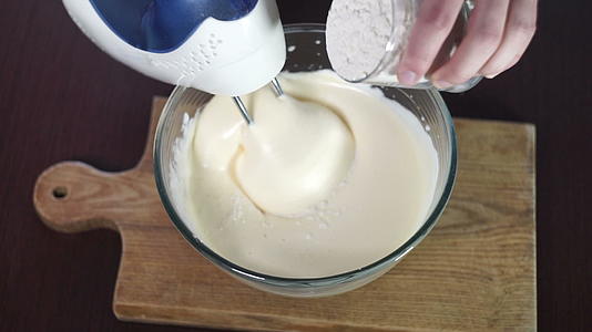 厨师在玻璃碗中加入面粉和面团用电动搅拌机在碗中搅拌视频的预览图
