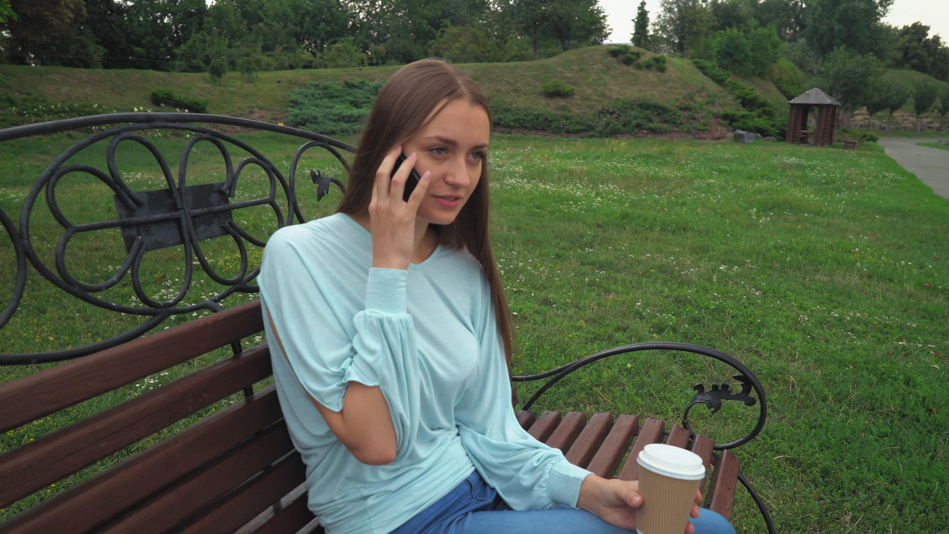 一个年轻女孩坐在公园年轻女孩通过电话交谈视频的预览图