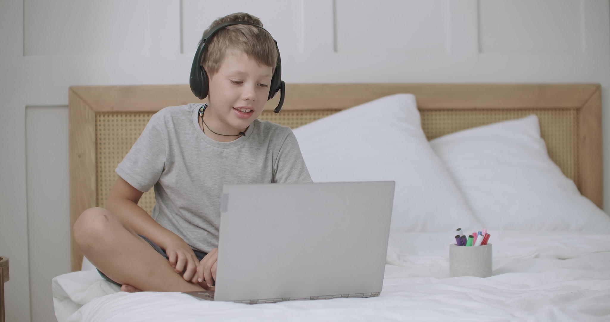 小男孩坐在家里的床上用笔记本在网上聊天视频的预览图