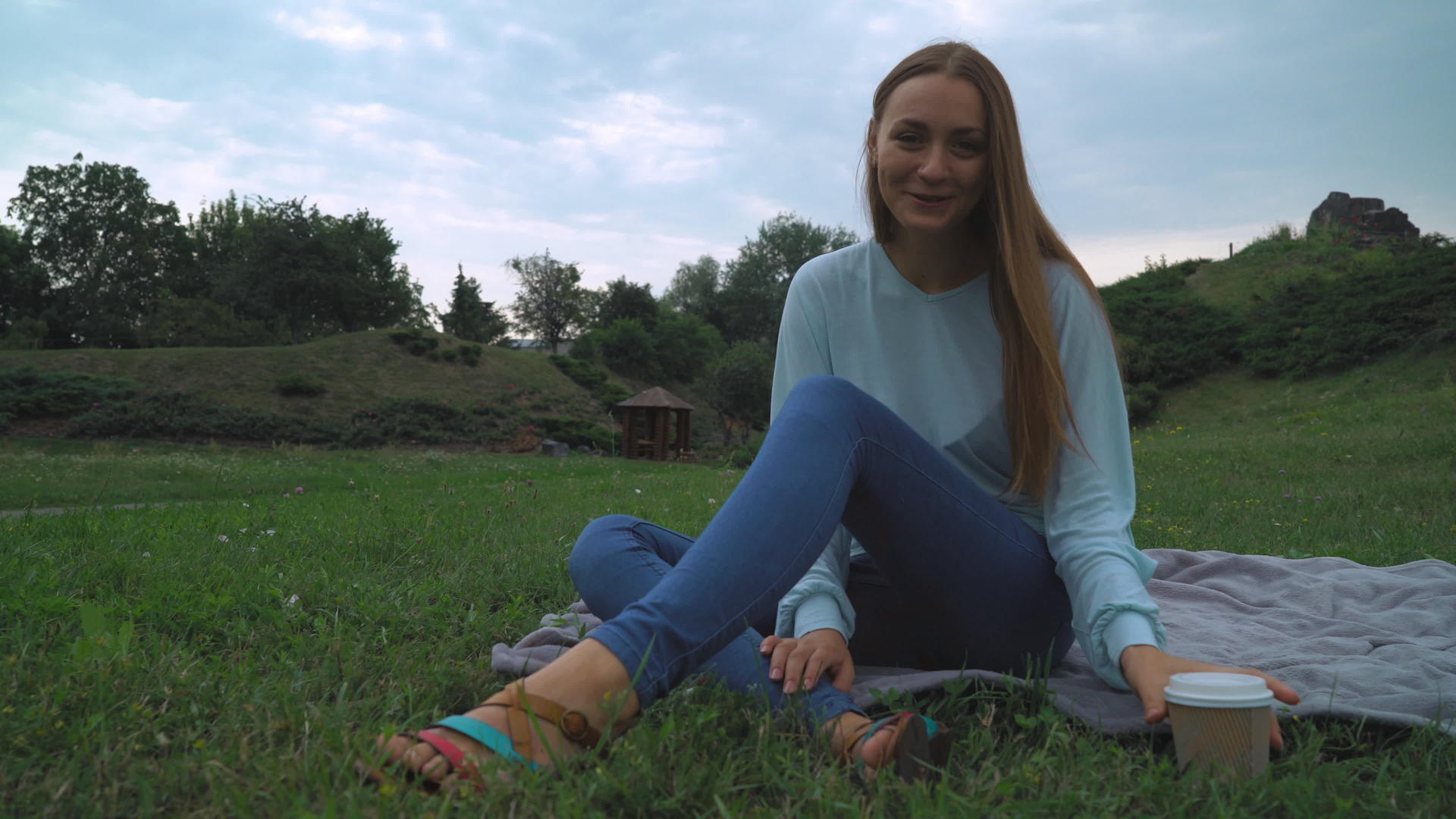 一个女孩坐在公园的草坪上喝咖啡笑着视频的预览图