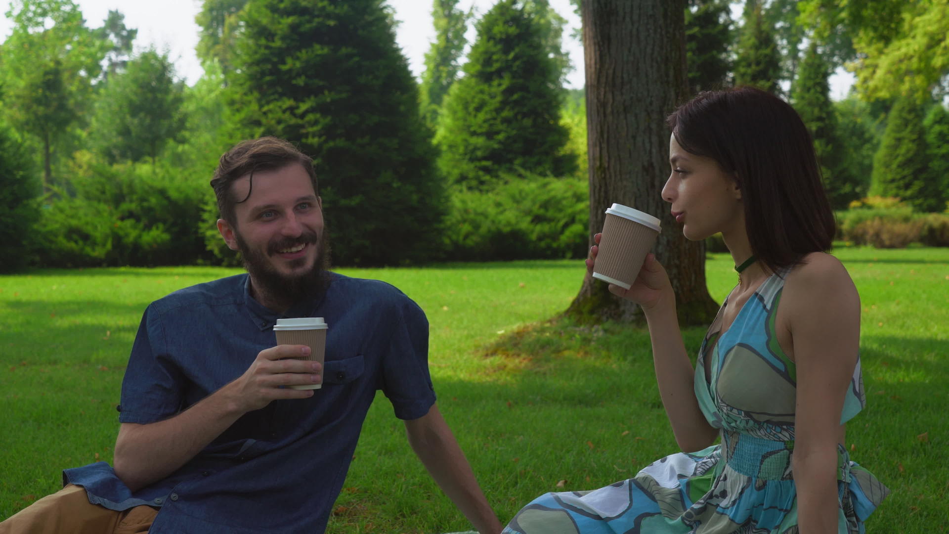 一对年轻夫妇坐在公园的地上喝咖啡视频的预览图