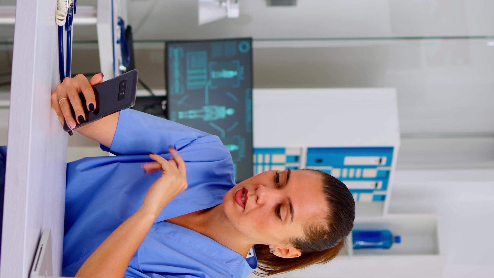 垂直视频护士在与远程医疗患者交谈时使用智能手机的护士垂直版视频的预览图