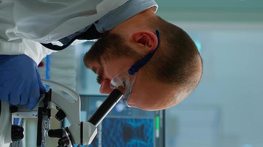 垂直视频男性科学家在医学发展实验室的显微镜下看医生垂直版视频的预览图