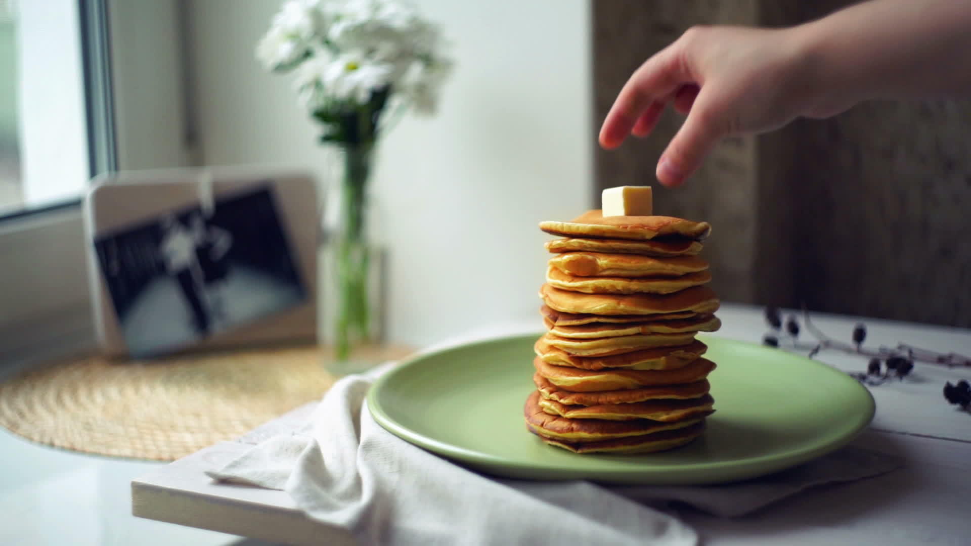 煎饼早餐时手在煎饼堆上放一块黄油视频的预览图