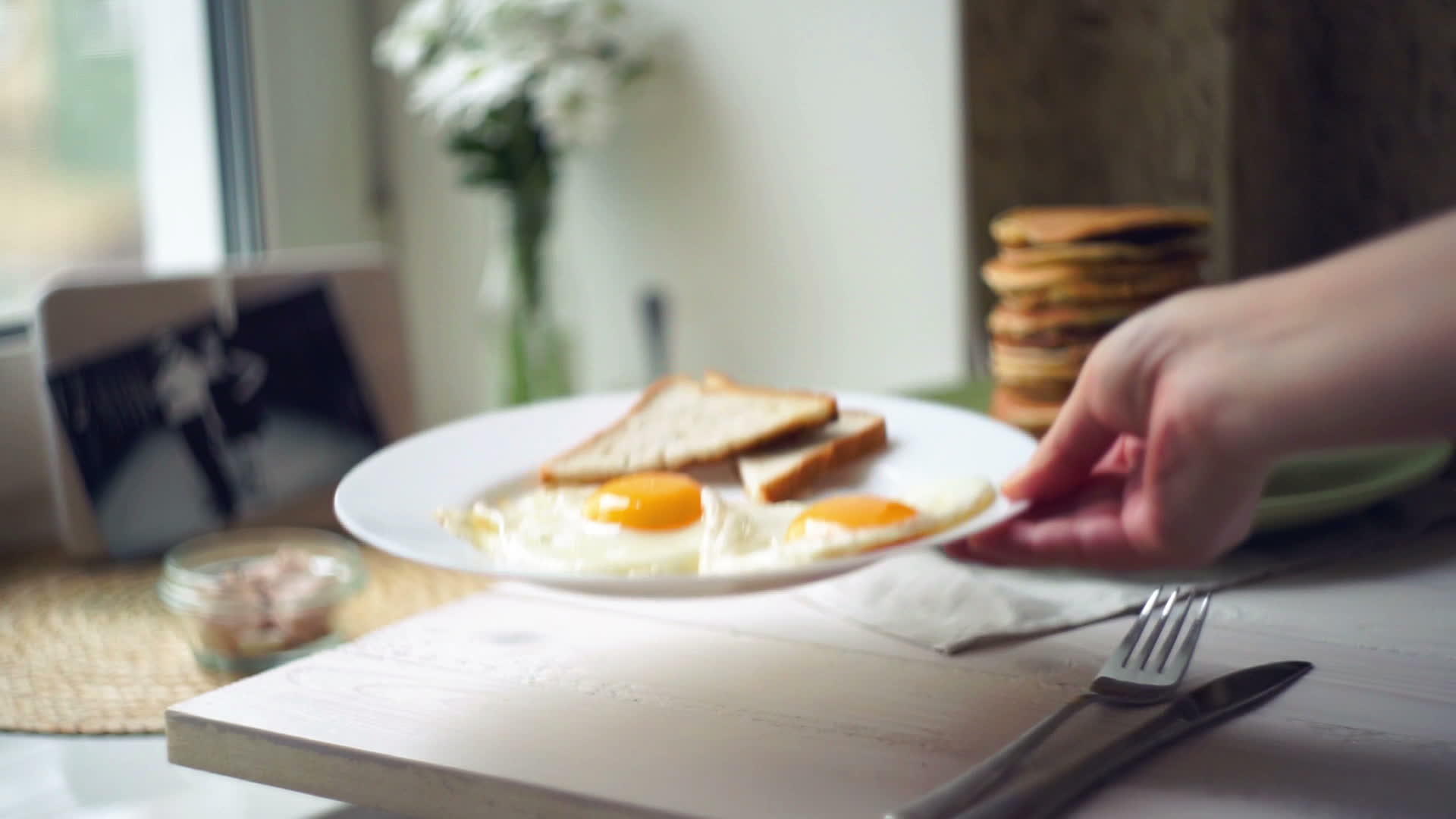 女人把盘子和煎蛋面包片放在厨房桌子上视频的预览图