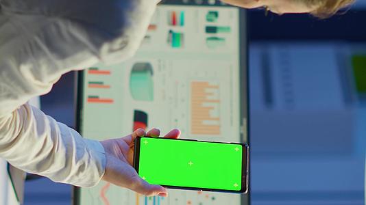 商业女性使用绿屏观看智能手机背面的场景视频的预览图
