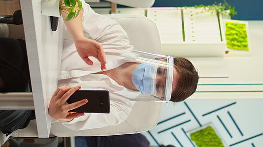 戴着口罩和口罩的女性通过视频向智能手机呼叫垂直版视频的预览图