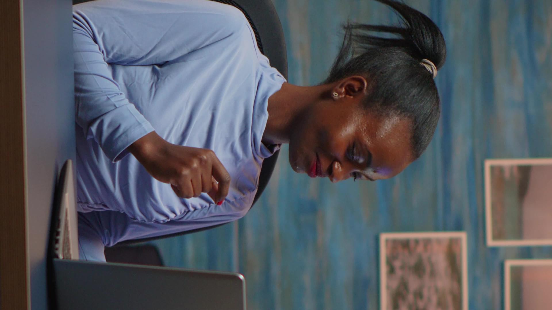 垂直视频微笑的非洲自由职业者在笔记本电脑上听音乐垂直版视频的预览图