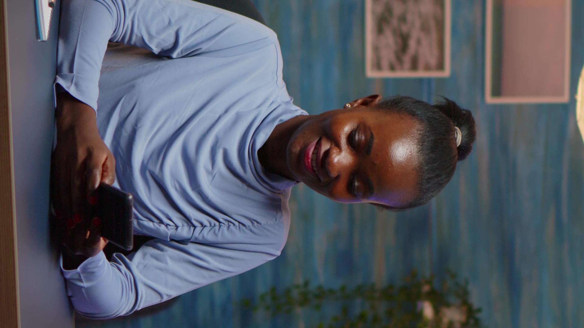 非洲女士在智能手机上打字的垂直视频视频的预览图