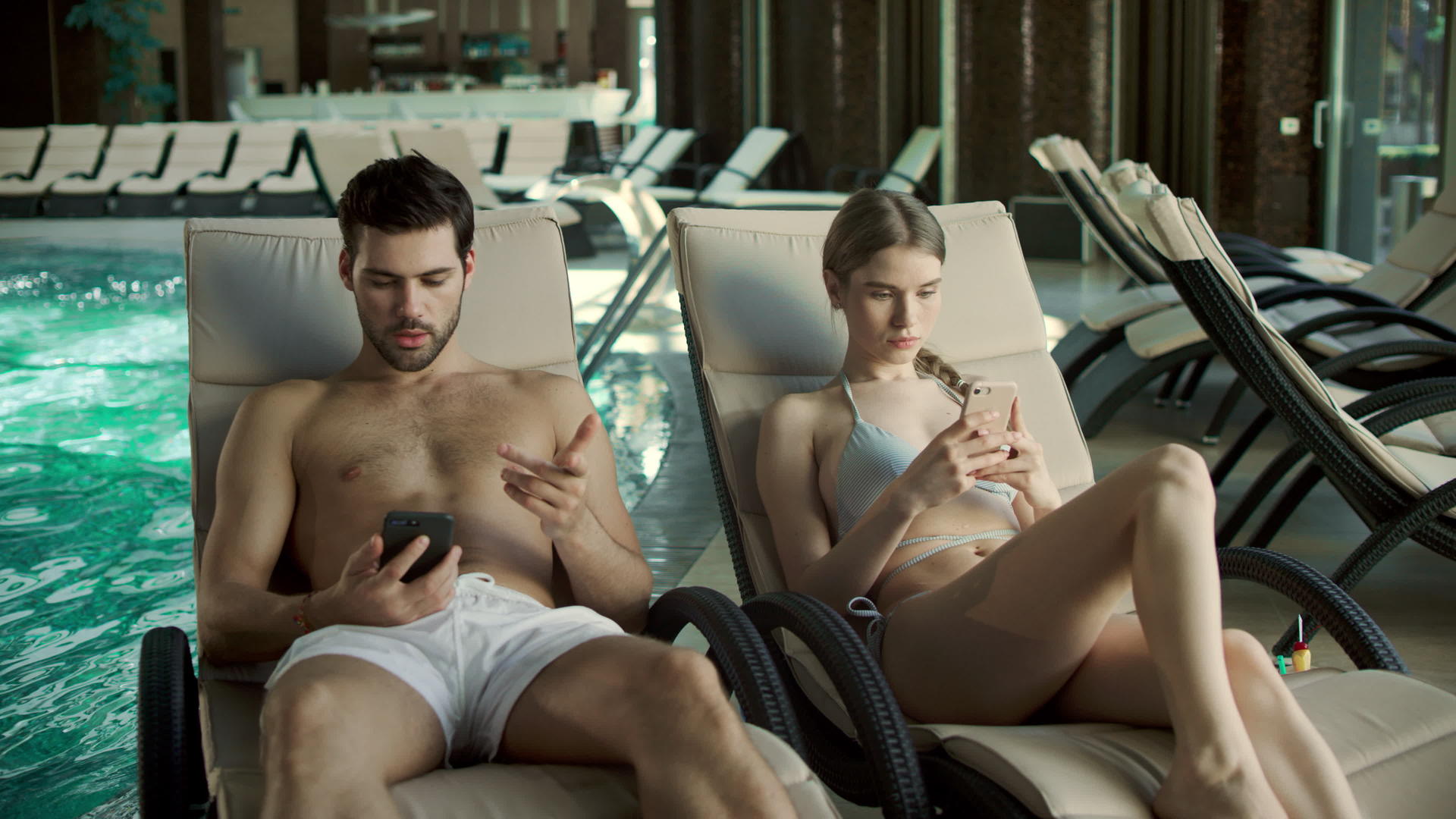 年轻夫妇在泳池附近看手机视频的预览图
