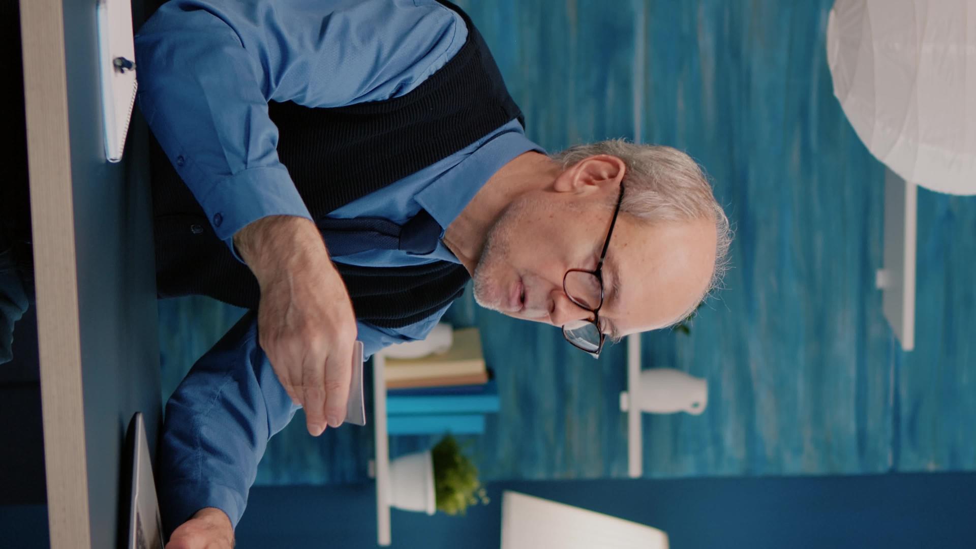 退休男子使用笔记本电脑信用卡在线支付退休垂直版视频的预览图