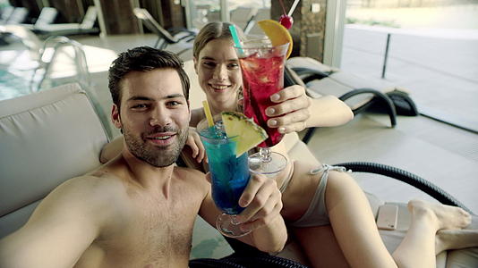 一对夫妇在游泳池附近用鸡尾酒自拍视频的预览图