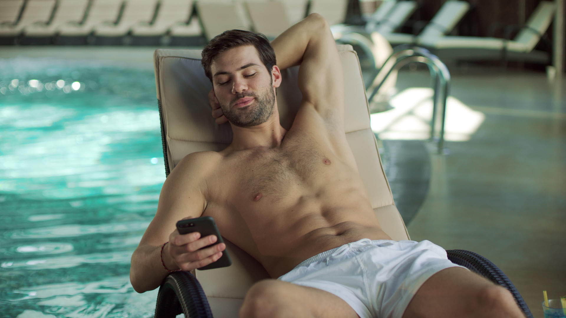 男人在游泳池边用手机视频的预览图