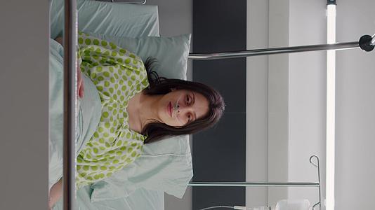 穿着鼻氧管的垂直视频患者看着床上的摄像头视频的预览图