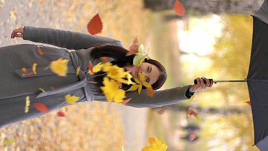美丽的女人举起一把有叶的伞然后它们掉了下来视频的预览图