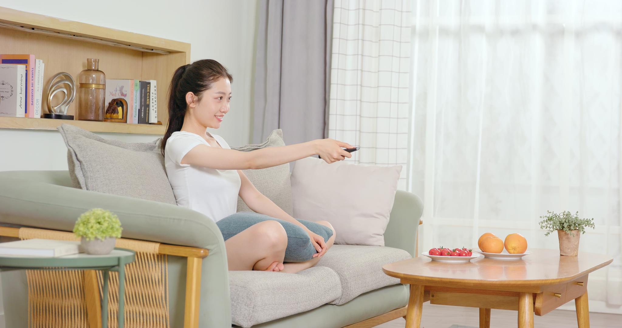 女孩盘腿坐在沙发上边看电视边吃水果视频的预览图