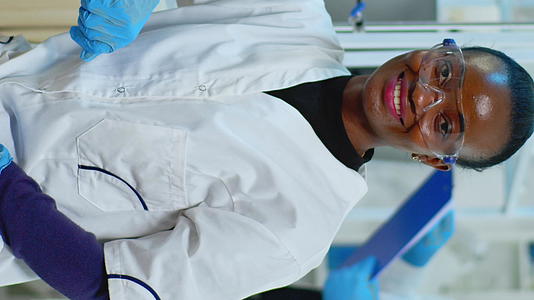 在科学实验室的相机上黑人女医生微笑着垂直版视频的预览图