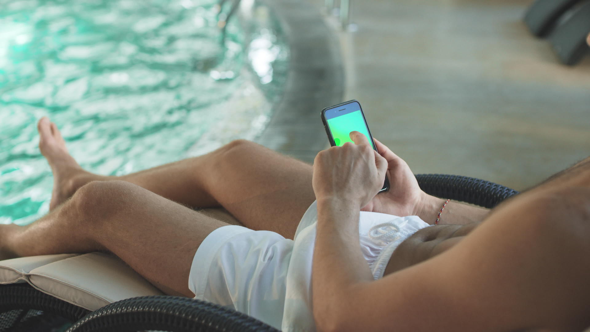 手持绿屏手机的男子在酒店的游泳池里视频的预览图