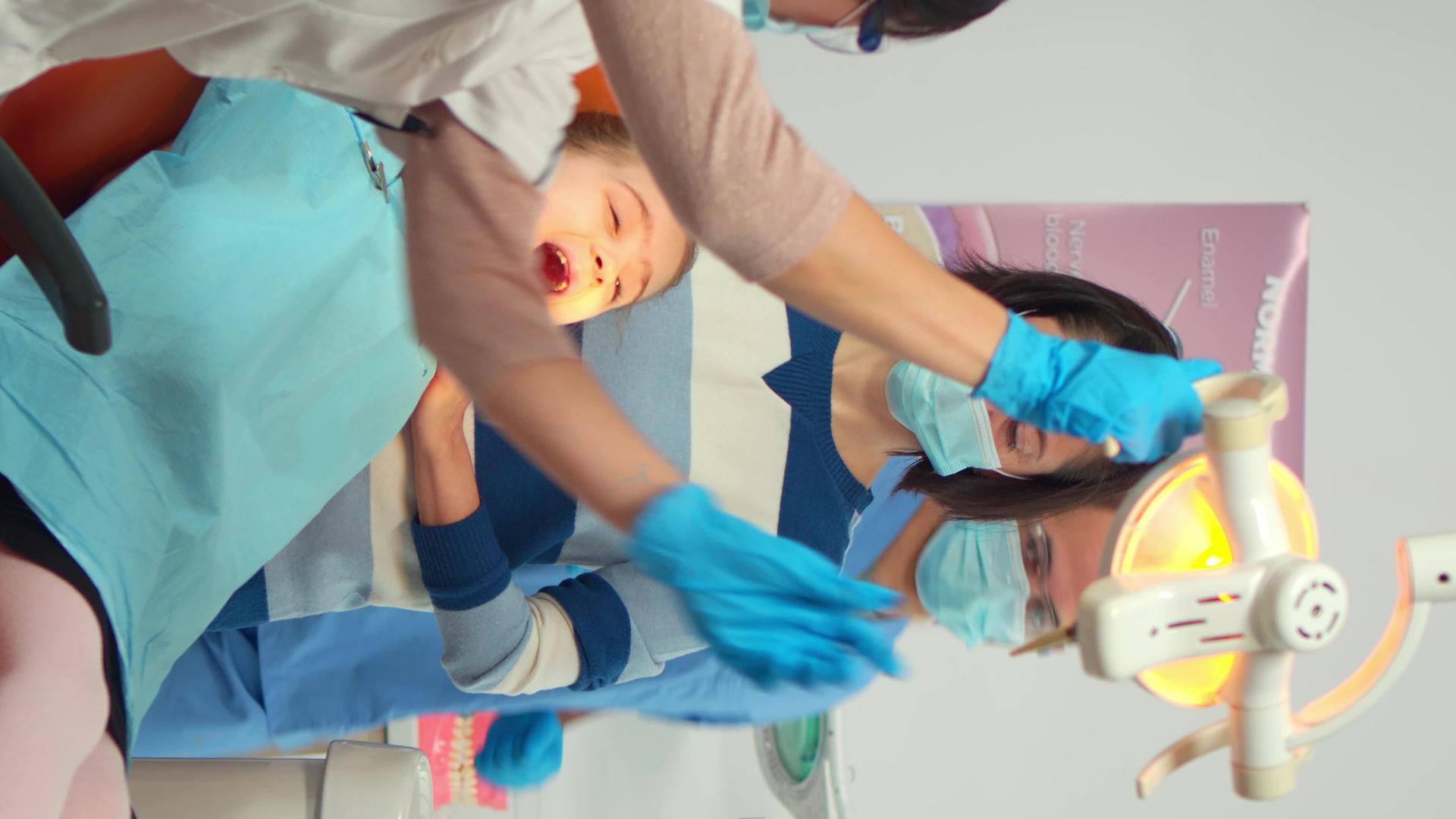 垂直视频录像牙医技术人员戴着手套向儿童患者解释这一过程垂直版视频的预览图