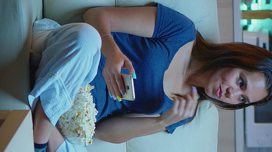 垂直视频女性在电话里吃爆米花视频的预览图