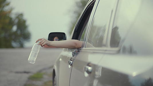 把塑料瓶扔在路上的汽车窗外的社会问题概念视频的预览图