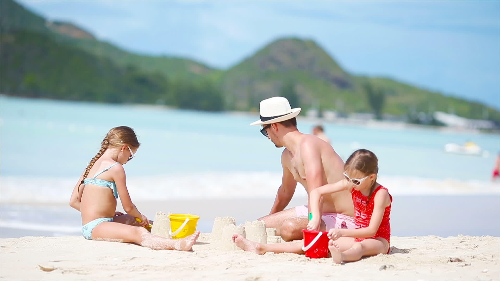 家庭在热带白色海滩制作沙堡父亲和两个女孩在热带海滩视频的预览图