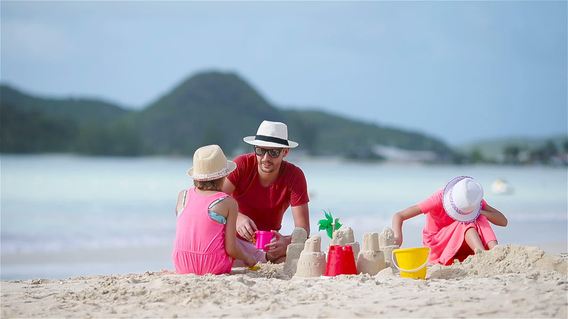 一个家庭在热带白色海滩制作沙堡视频的预览图