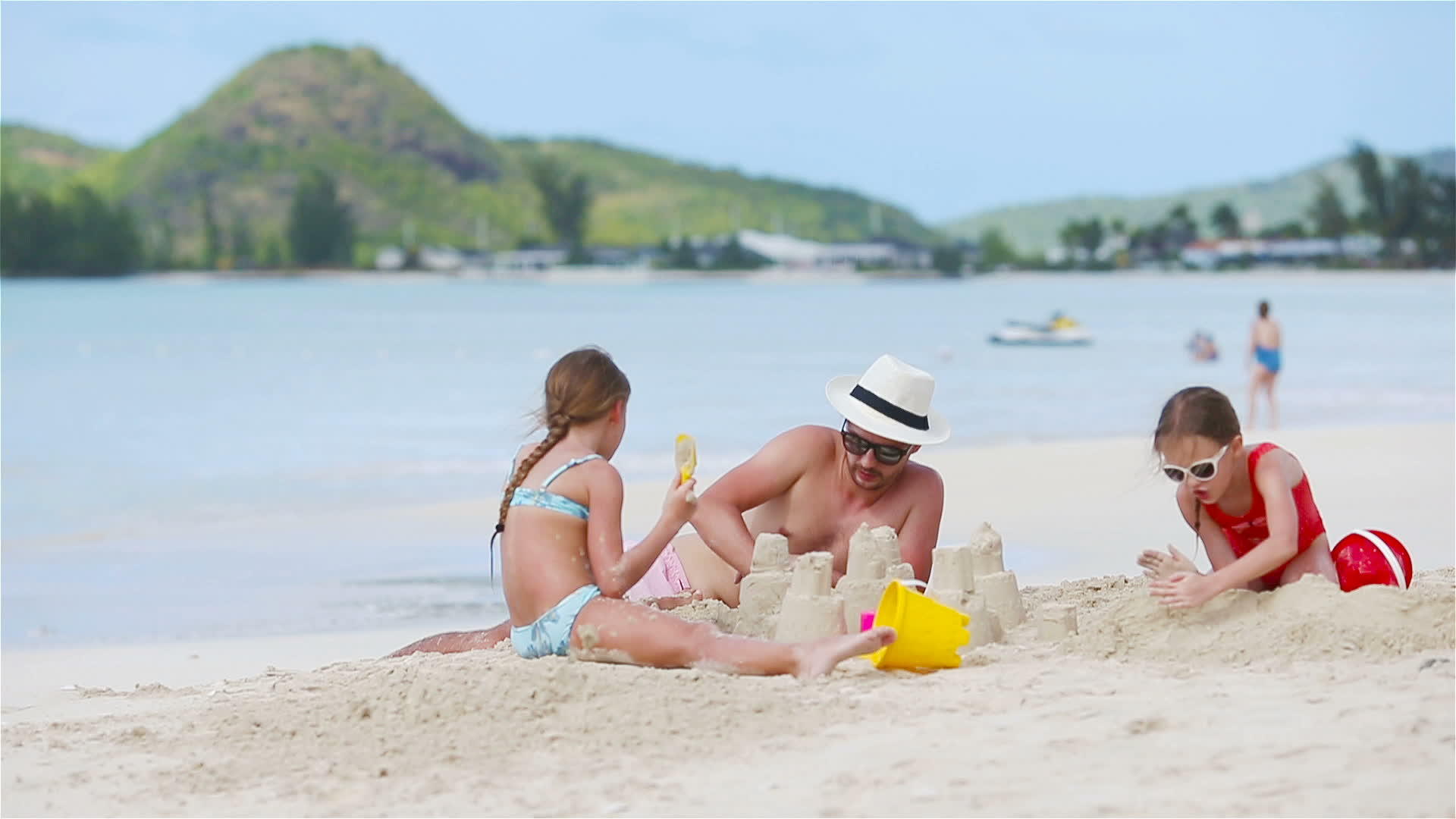 父亲和两个女孩在热带海滩玩沙子视频的预览图