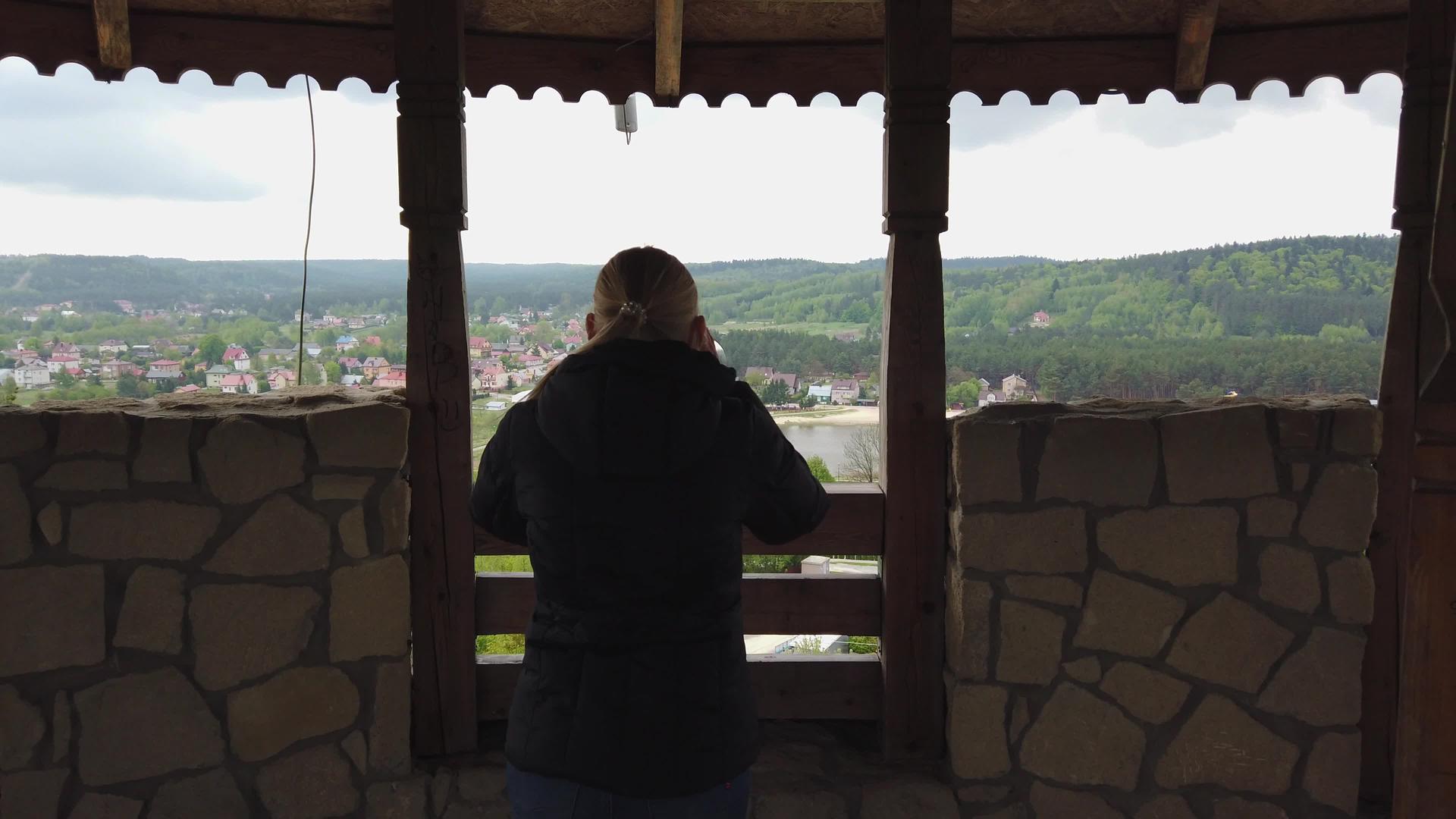用望远镜观察古城堡附近山谷周围迷人的女性游客视频的预览图