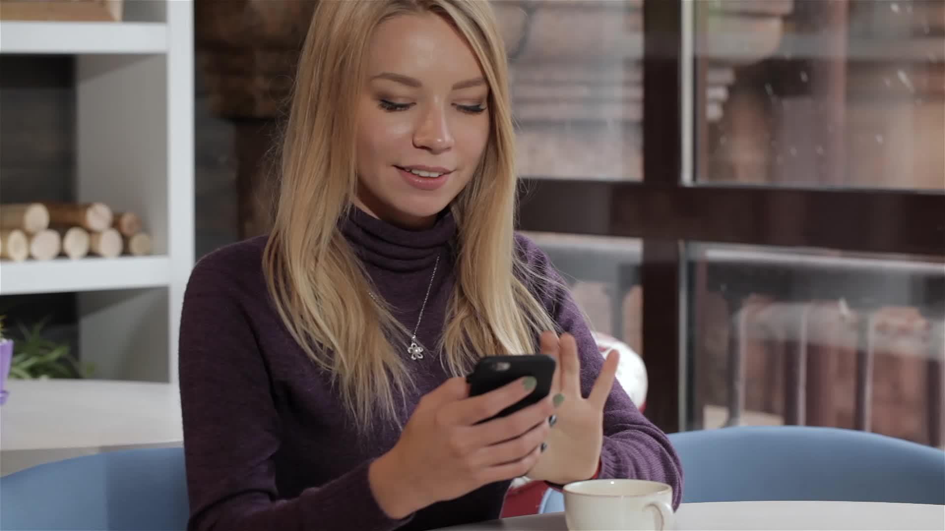 女孩在咖啡馆使用智能手机视频的预览图