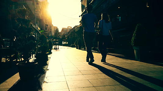 剪影夫妇在欧洲城市的石板路上快乐地走在夕阳下视频的预览图