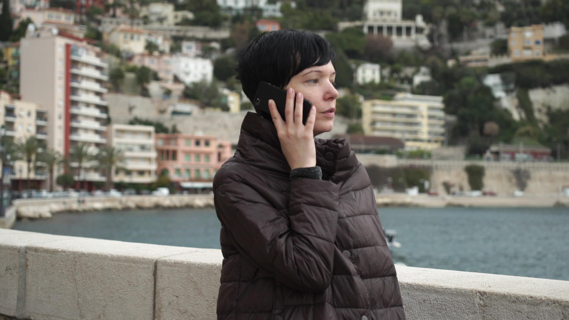 女性在城市海边使用智能手机视频的预览图