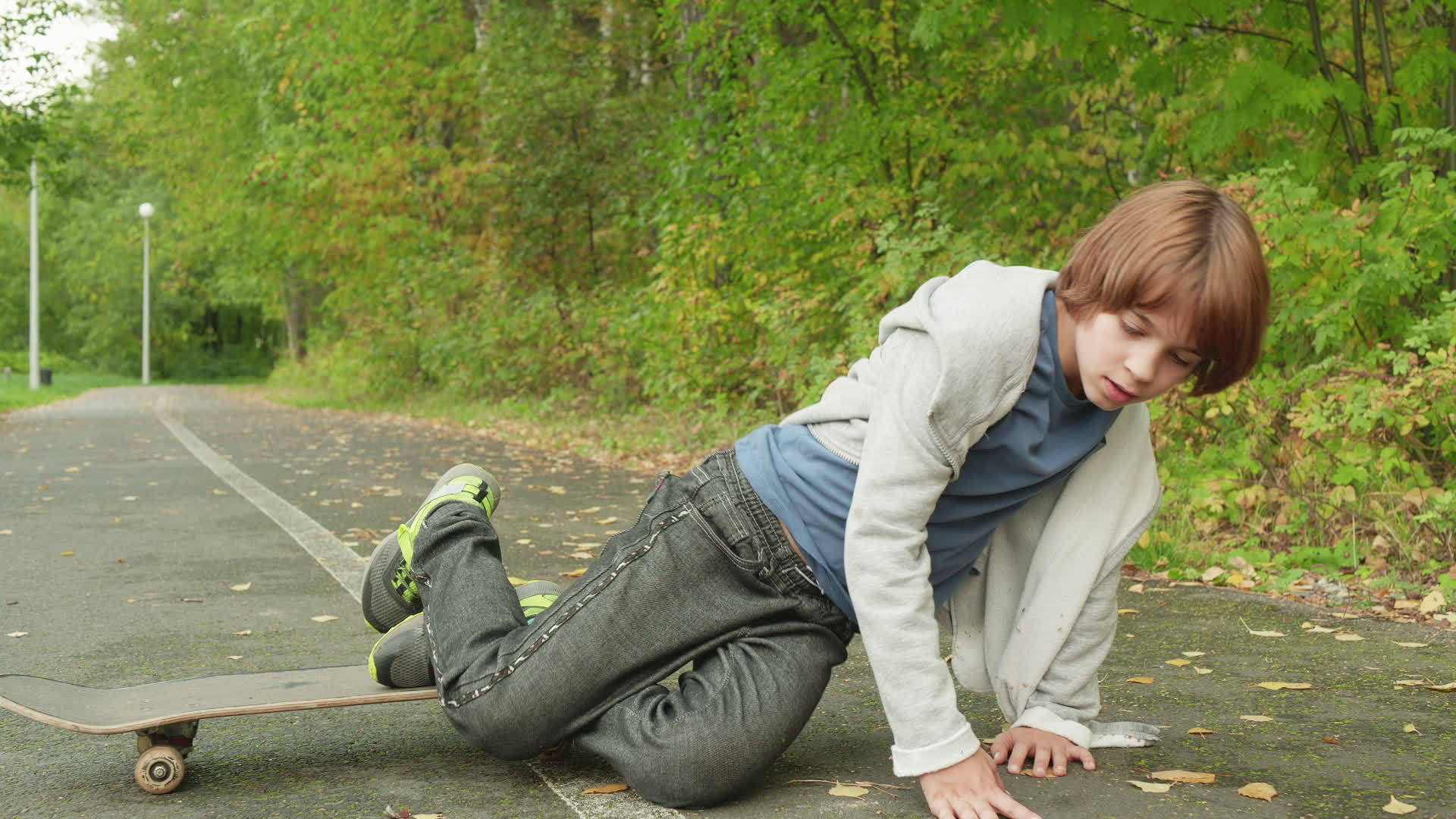 年轻的滑板手在夏天公园的沥青路上从滑板上摔了下来视频的预览图