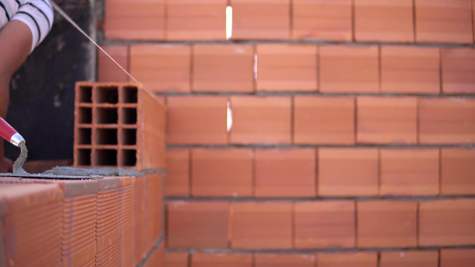 建筑工人在建筑工地上砌砖砌砖形成砖墙视频的预览图
