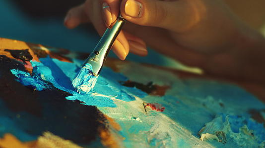 女人画布上的油画在画家调色板上搅拌颜料视频的预览图