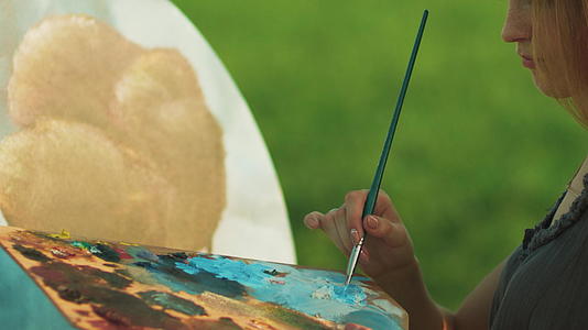 女画家在艺术调色板上涂上油漆和漆刷视频的预览图
