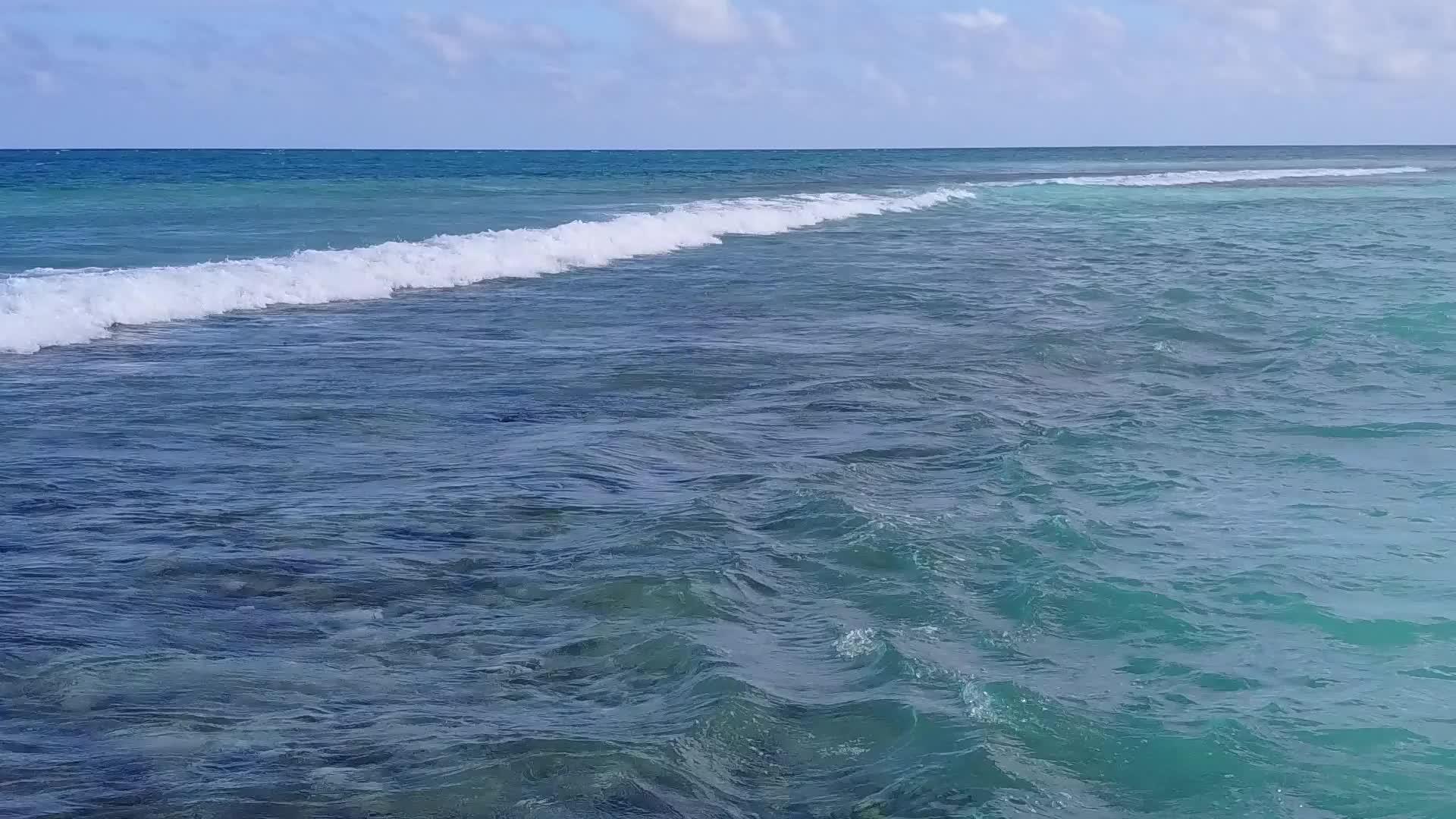 蓝色清澈的海洋在阳光下的白色海滩旁边视频的预览图