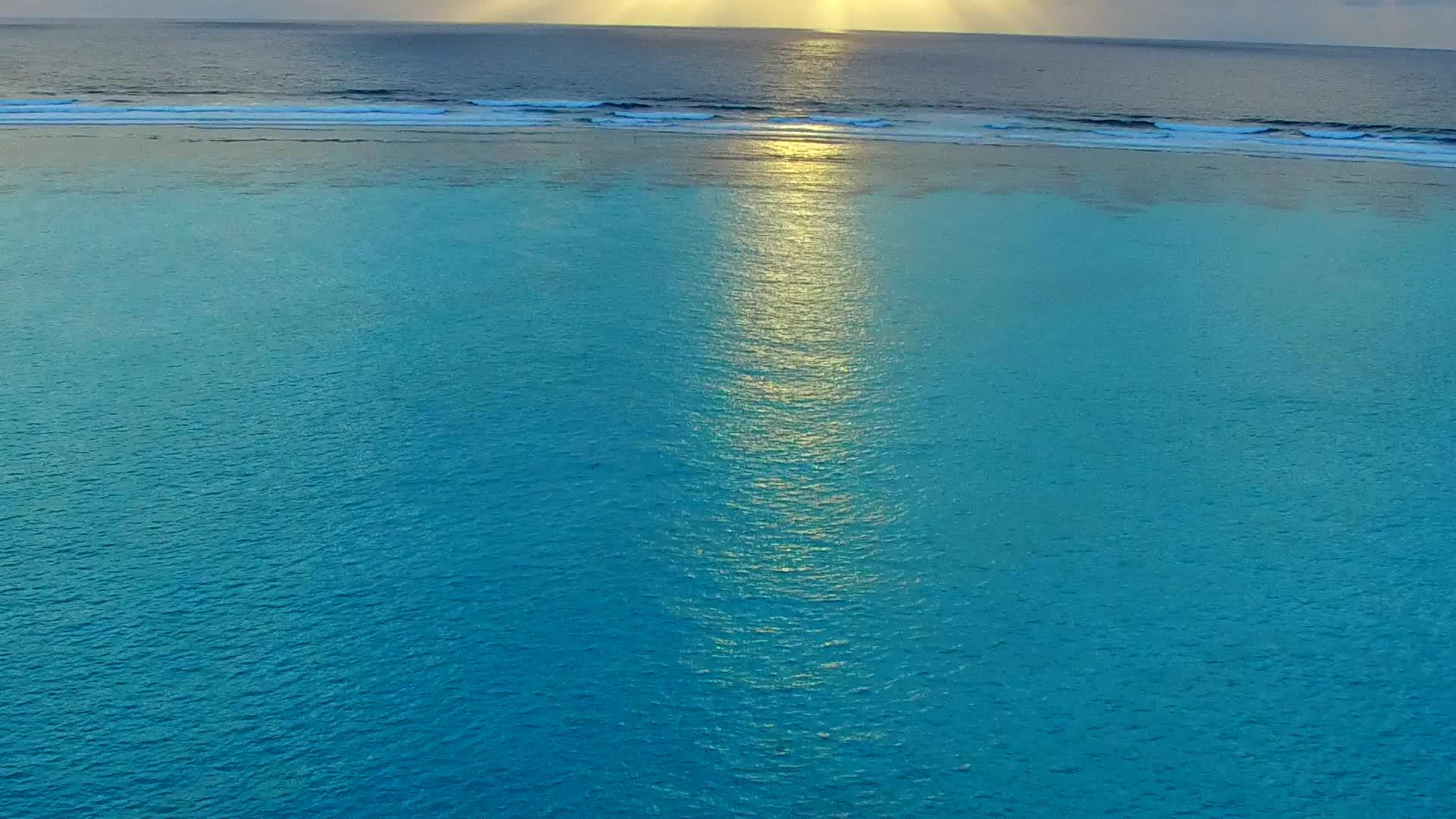 蓝色的海洋在阳光下的白色海滩旁边视频的预览图