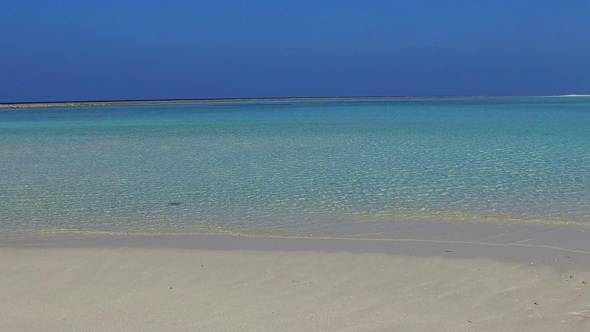 日落前蓝色环礁湖和白色滩背景下阳光明媚的海岸海滩视频的预览图
