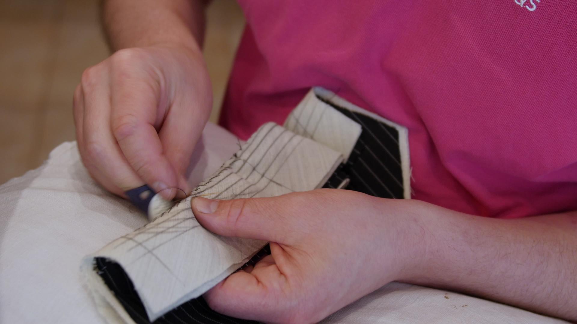 时装设计师用手在一件定制夹克下圈缝制衣领针视频的预览图