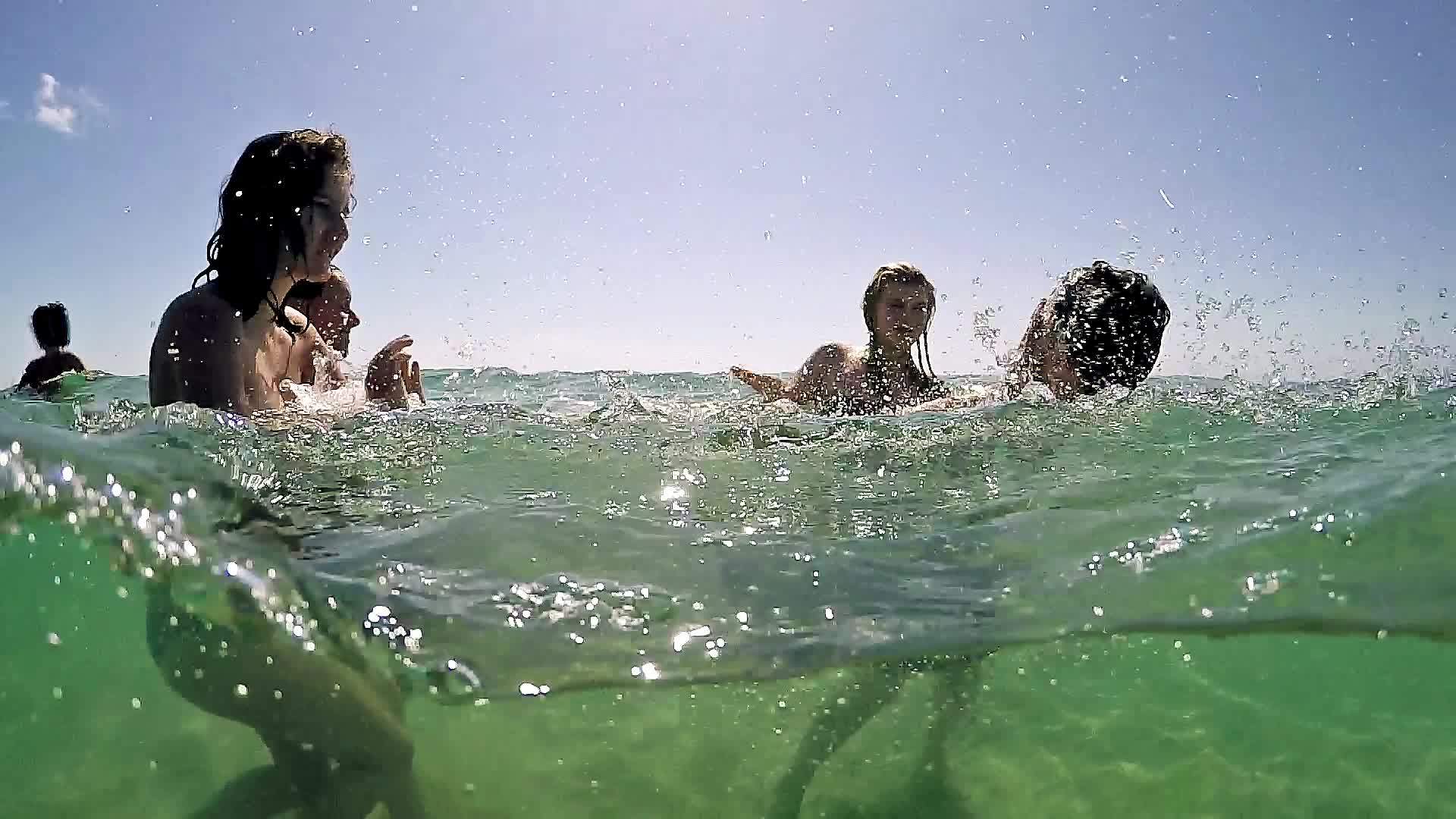 人们在湖中互相飞溅的肖像在水下半角慢慢移动Gopro视频的预览图