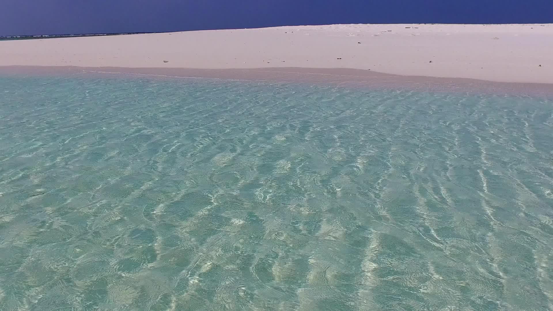 蓝色清澈的海洋在阳光下的白色海滩旁边视频的预览图